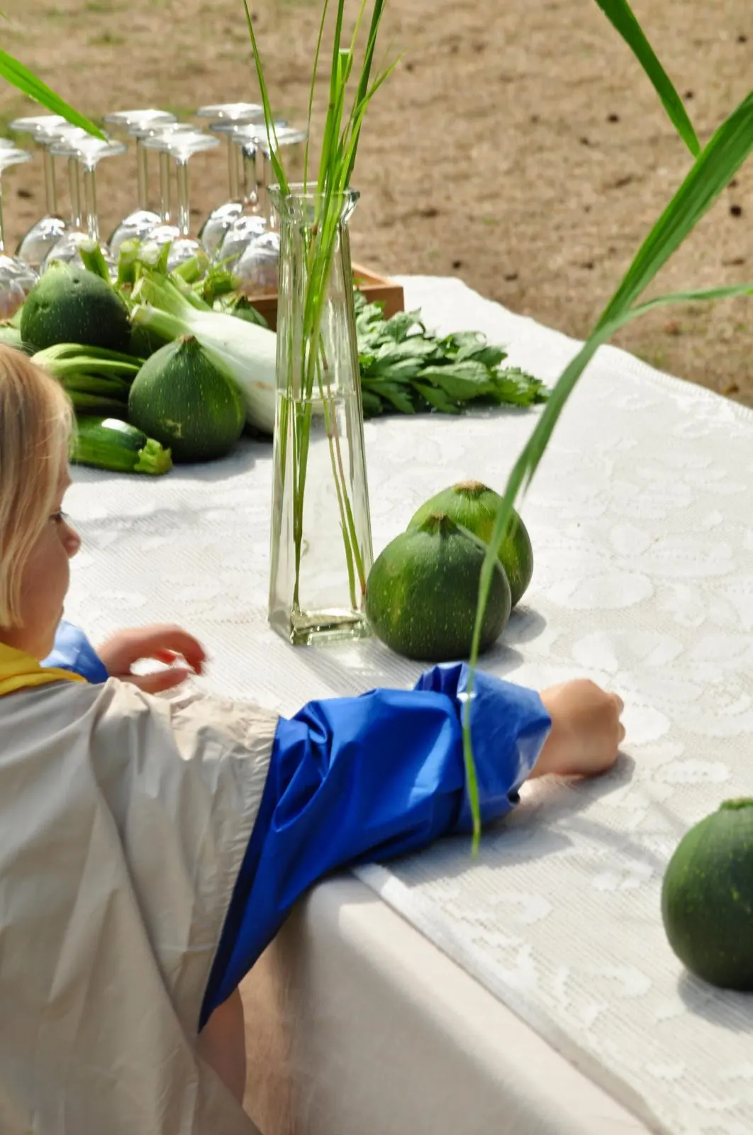 Une enfant devant la table dressée, courgettes du potager et verres