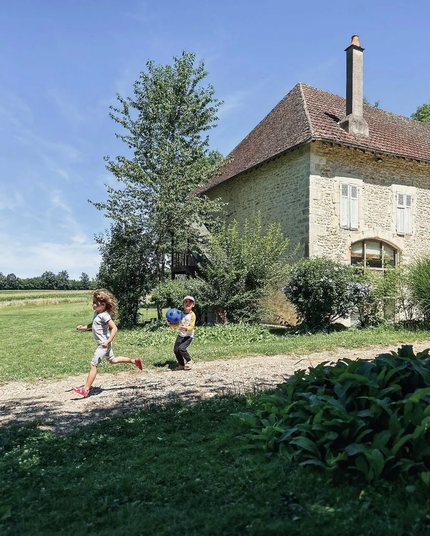 Des enfants courent devant la longère