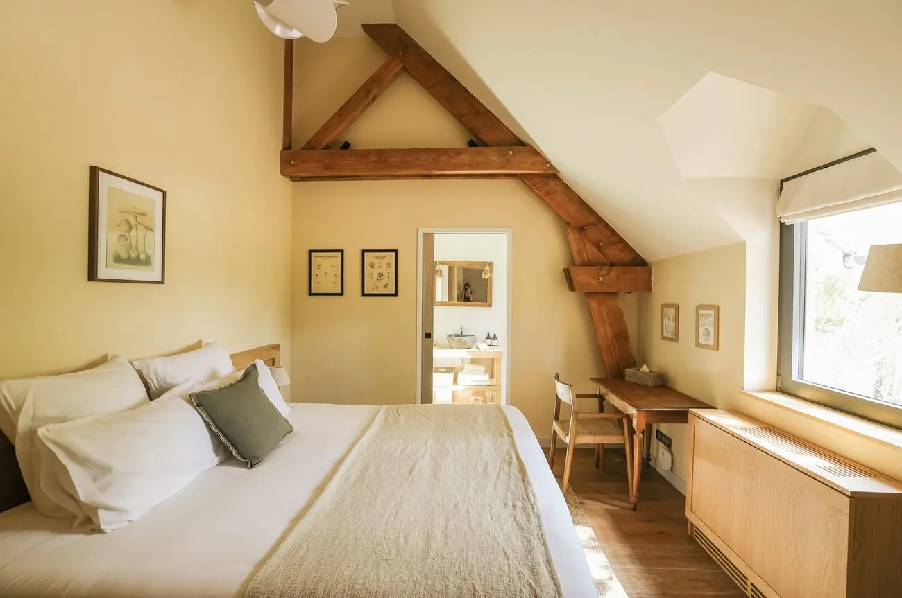 Chambre claire sous la charpente avec bureau et fenêtre