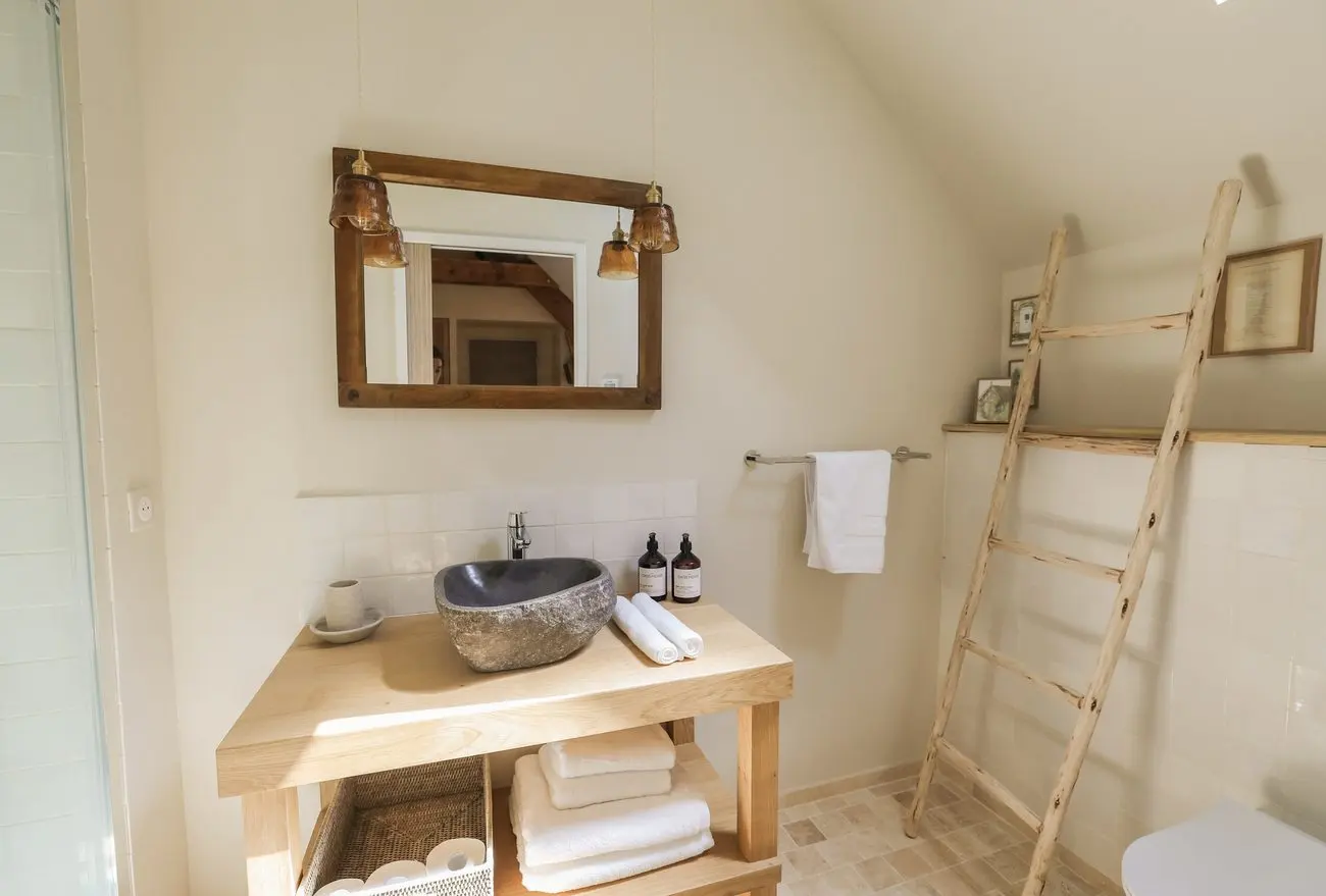 Salle de bain claire, vasque en pierre et échelle en bois