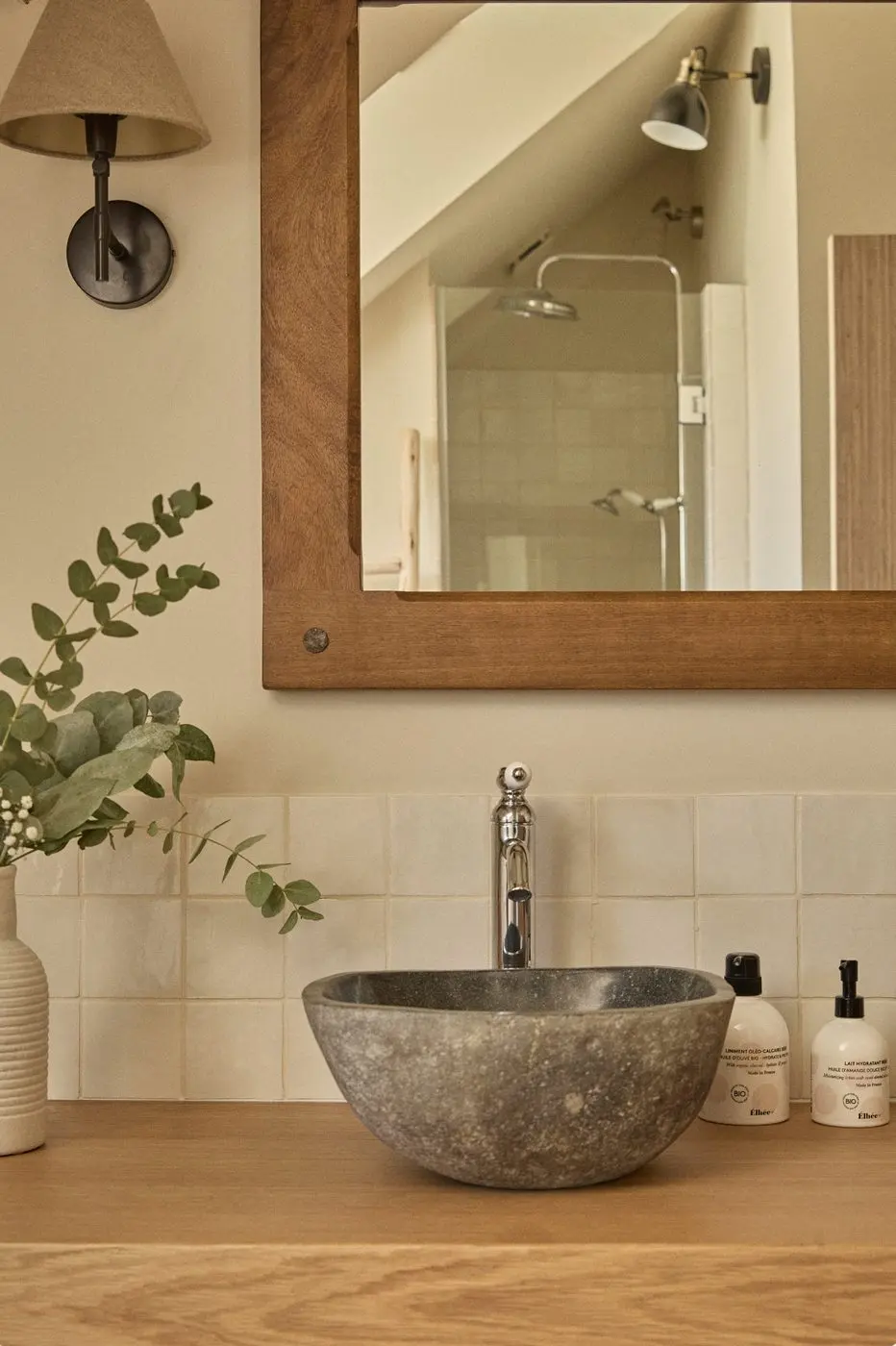 Vasque en pierre, miroir en bois et douche en reflet