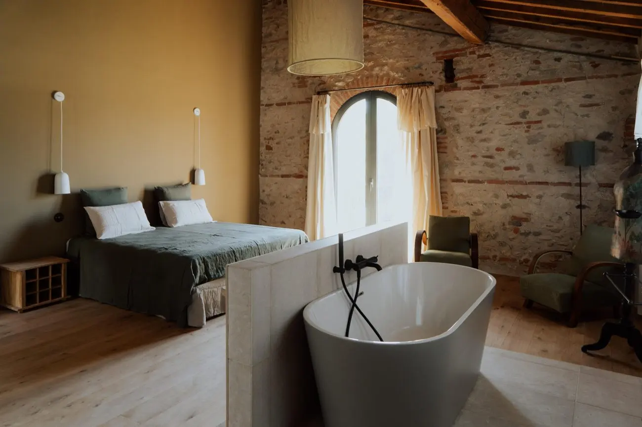 Chambre du gîte, baignoire ouverte et mur de pierre