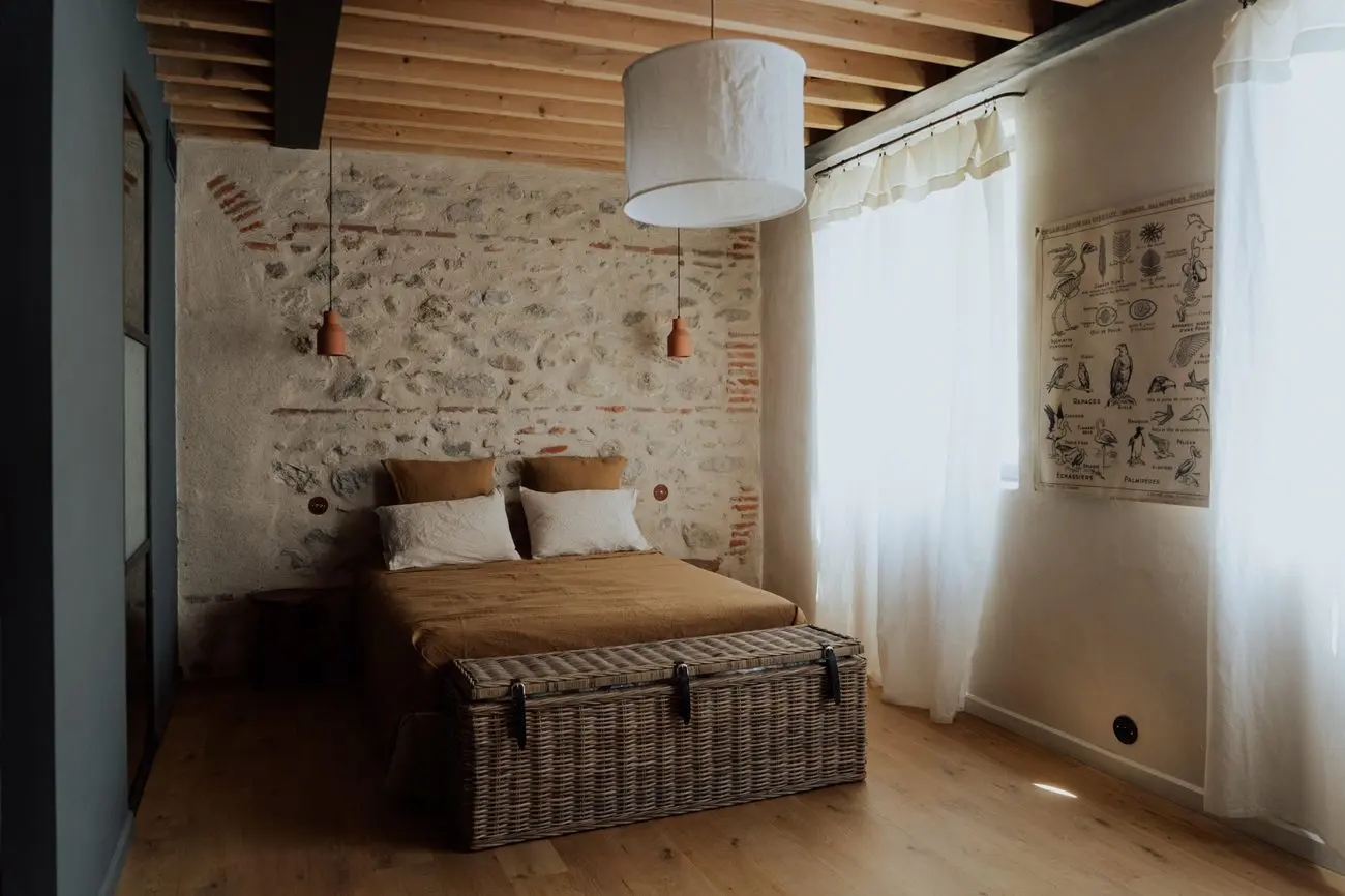 Chambre du gîte, mur de pierre et malle en osier